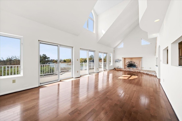 unfurnished living room featuring wood-type flooring, a high ceiling, and a fireplace