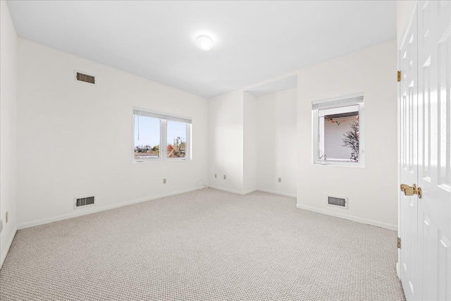 empty room featuring visible vents, baseboards, and light colored carpet