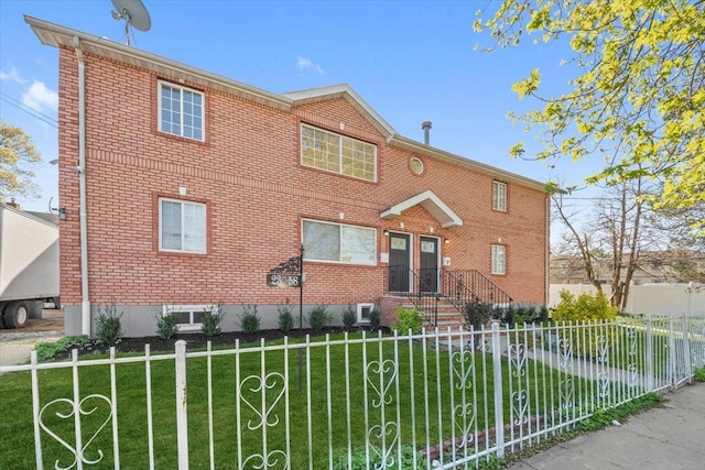 view of front of house featuring fence private yard, a front lawn, and brick siding