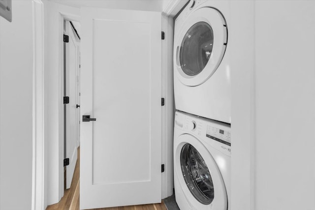 laundry room with laundry area, stacked washer and dryer, and wood finished floors