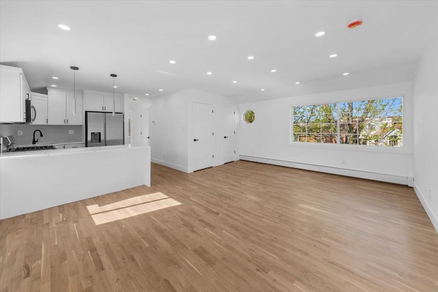 unfurnished living room featuring baseboards, light wood-type flooring, a baseboard heating unit, and recessed lighting
