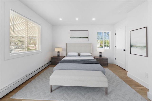 bedroom with recessed lighting, baseboards, a baseboard heating unit, and wood finished floors