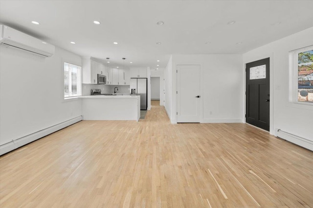 unfurnished living room with recessed lighting, a wall mounted air conditioner, light wood-style flooring, and a wealth of natural light