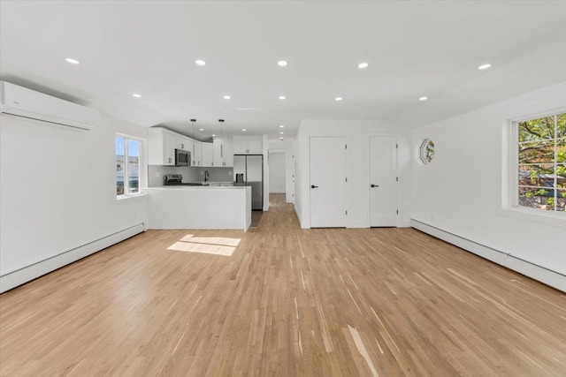 unfurnished living room featuring light wood-type flooring, recessed lighting, a wall mounted AC, and baseboard heating