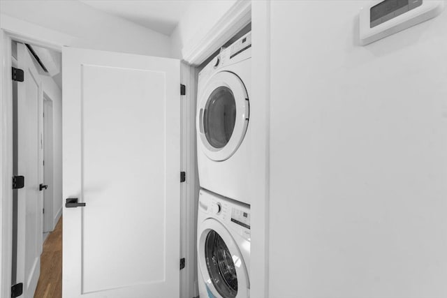 laundry room with stacked washer / drying machine, wood finished floors, and laundry area