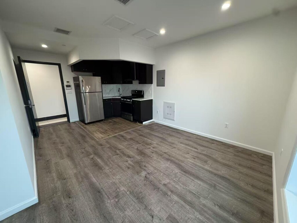 42-08 Bowne St Unit 2A, Flushing, NY 11355 - kitchen with dark cabinetry, dark wood finished floors, range with gas stovetop, freestanding refrigerator, and electric panel