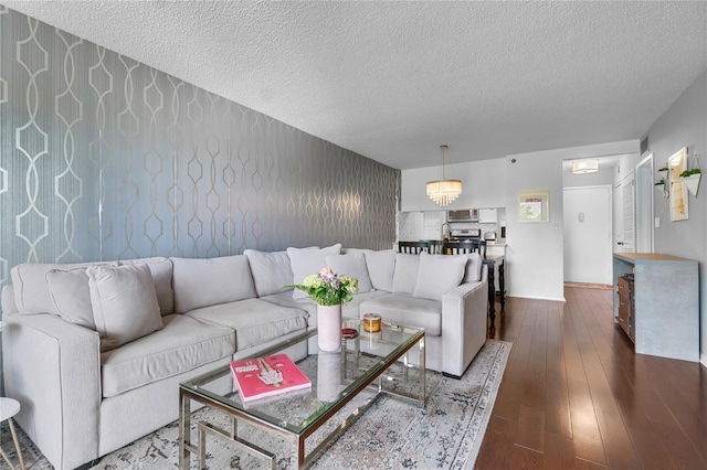 living room with a textured ceiling, baseboards, and wood finished floors