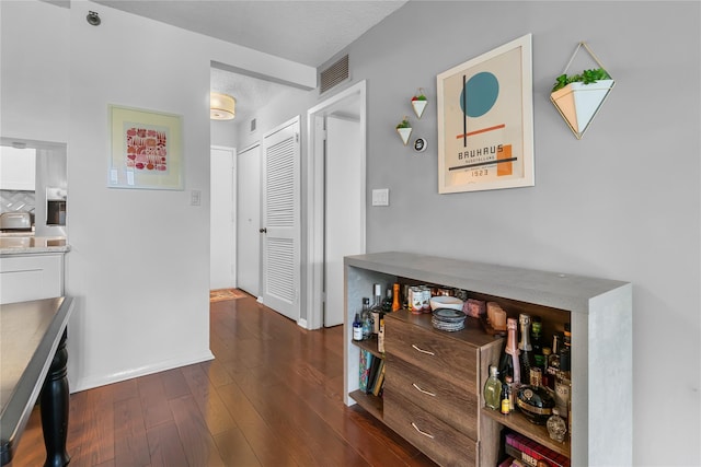 interior space with visible vents, baseboards, and dark wood-style floors