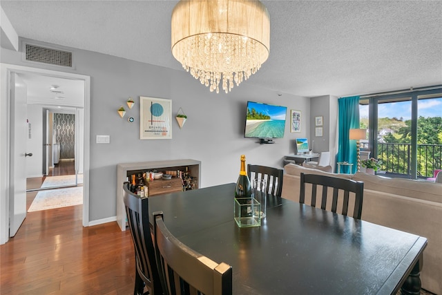 dining space featuring an inviting chandelier, a textured ceiling, visible vents, baseboards, and dark wood-style floors