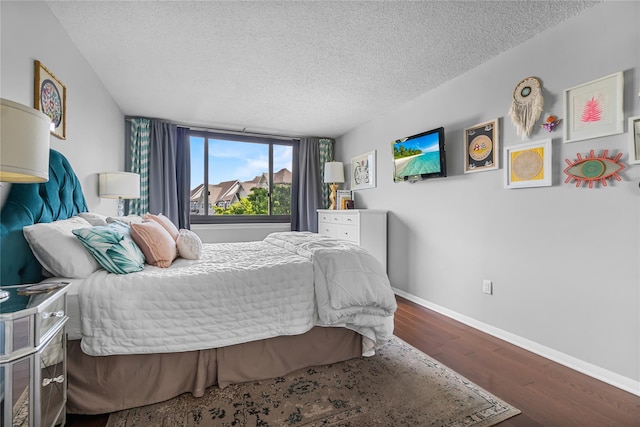 bedroom with a textured ceiling, baseboards, and wood finished floors