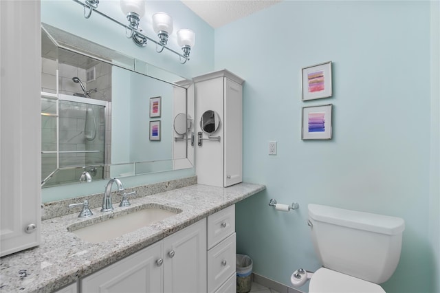 full bath featuring vanity, toilet, tiled shower, and a textured ceiling
