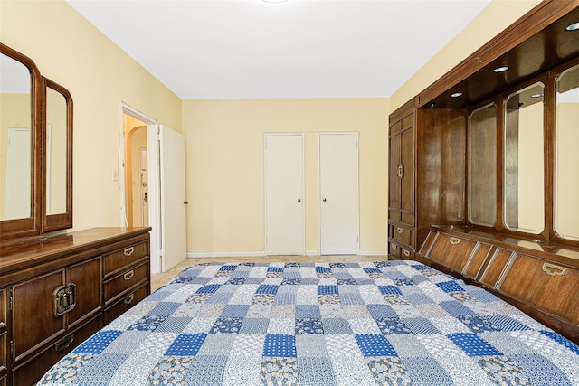 unfurnished bedroom featuring arched walkways and light carpet