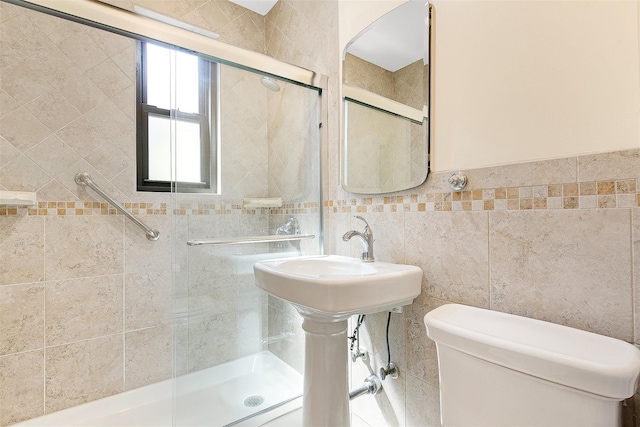 bathroom with a stall shower, toilet, and tile walls