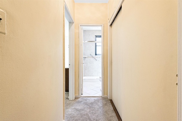 hall with baseboards and light colored carpet