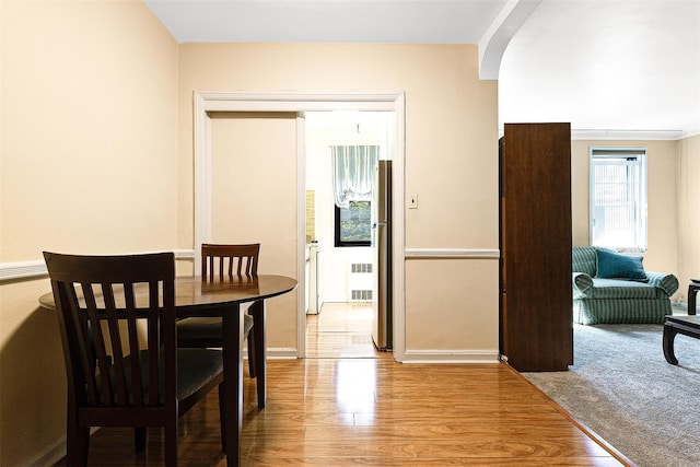 dining area with baseboards, light wood-style flooring, and radiator heating unit