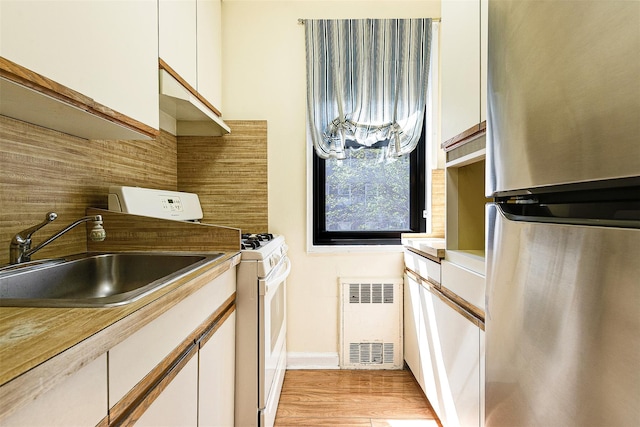 laundry room with cabinet space, a sink, baseboards, light wood-type flooring, and washing machine and dryer