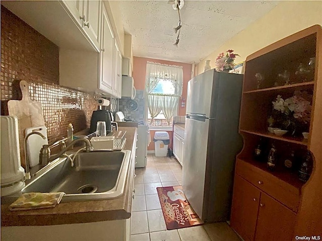 kitchen featuring a sink, stove, freestanding refrigerator, light tile patterned floors, and white microwave