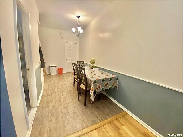 dining space with an inviting chandelier, baseboards, and wood finished floors