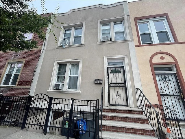 multi unit property with cooling unit, a fenced front yard, a gate, and stucco siding