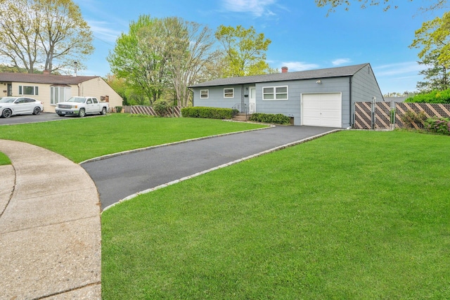 view of front facade featuring a chimney, driveway, fence, an attached garage, and a front lawn