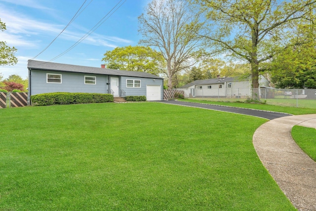 view of front of property featuring a front yard, aphalt driveway, an attached garage, and fence