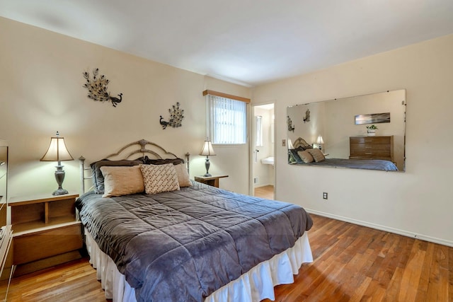 bedroom featuring wood finished floors, baseboards, and ensuite bathroom