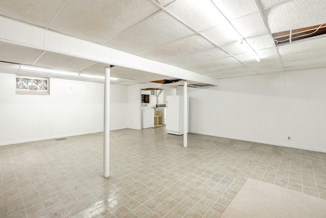 finished below grade area with a paneled ceiling, light floors, and baseboards