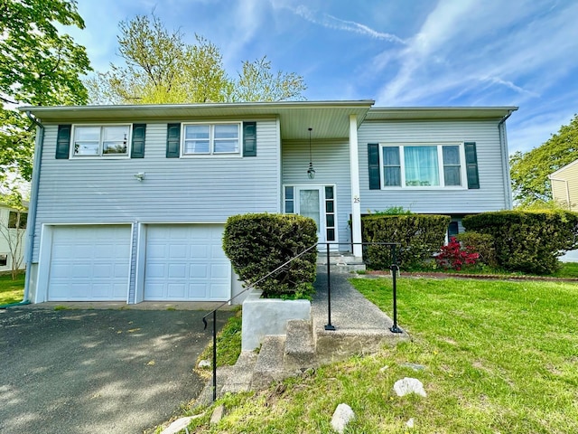 raised ranch featuring an attached garage, aphalt driveway, and a front yard