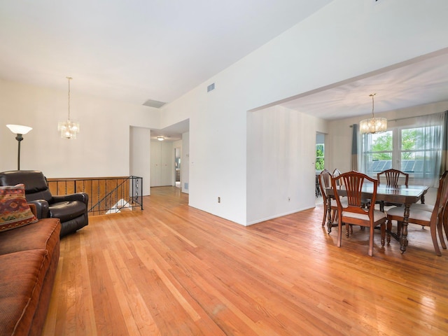 living area with an inviting chandelier, light wood-style flooring, and visible vents