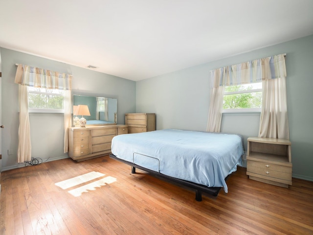 bedroom with baseboards, wood-type flooring, and visible vents