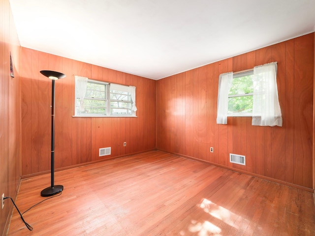 empty room featuring visible vents, wood finished floors, and a wealth of natural light