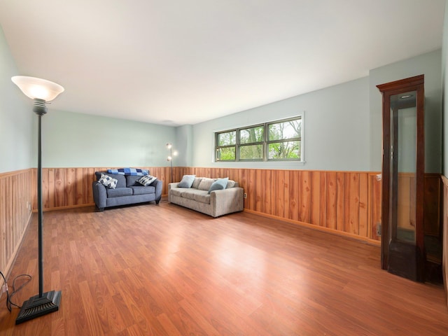 living room featuring wooden walls, a wainscoted wall, and wood finished floors