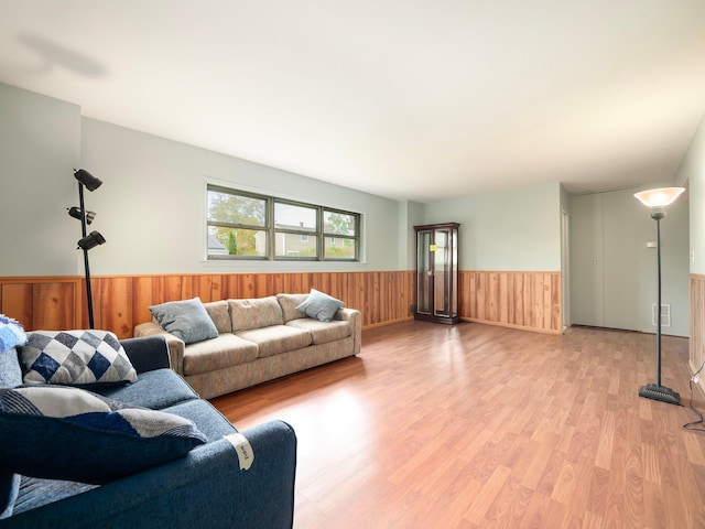 living area featuring wooden walls, wainscoting, light wood-type flooring, and visible vents