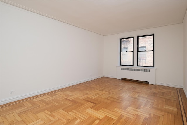 spare room featuring radiator and baseboards