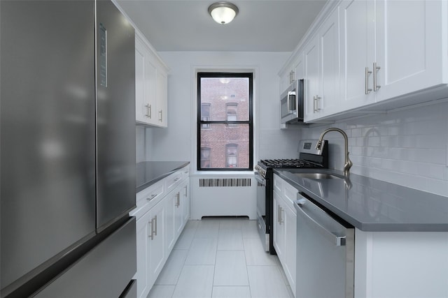 kitchen featuring a sink, white cabinets, dark countertops, stainless steel appliances, and tasteful backsplash