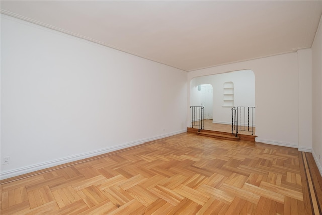 empty room with baseboards and arched walkways