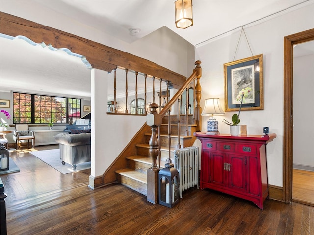staircase with radiator heating unit, baseboards, and wood finished floors