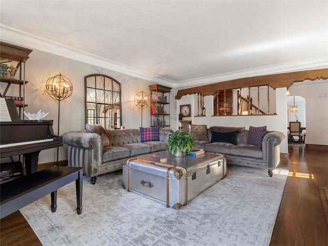 living room featuring crown molding, arched walkways, wood finished floors, and a chandelier