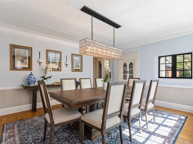 dining space featuring baseboards, ornamental molding, and wood finished floors
