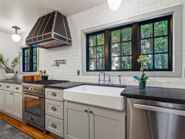 kitchen with plenty of natural light, dark countertops, wall chimney range hood, and stainless steel appliances