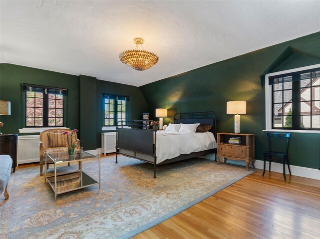 bedroom with baseboards, wood finished floors, vaulted ceiling, and radiator heating unit