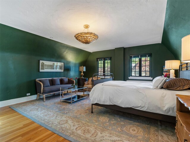 bedroom with baseboards, wood finished floors, and vaulted ceiling