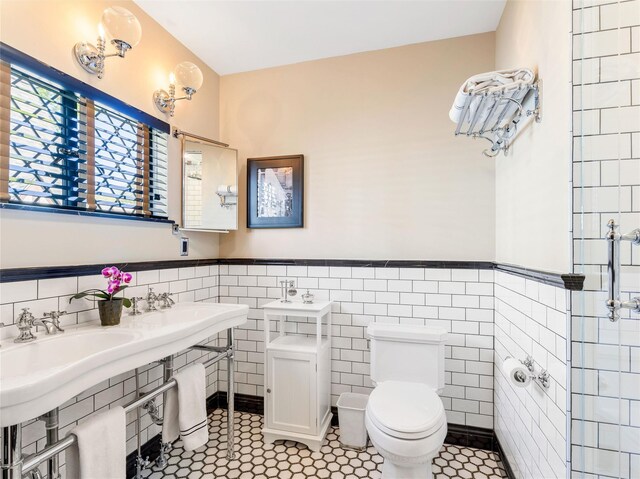 bathroom featuring a wainscoted wall, tile patterned flooring, toilet, and tile walls