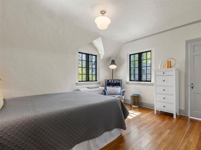 bedroom with baseboards, vaulted ceiling, and hardwood / wood-style floors