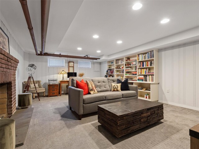 living room featuring a decorative wall, a brick fireplace, recessed lighting, and light colored carpet