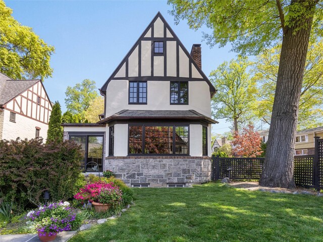 back of property featuring a lawn, stucco siding, a chimney, and fence
