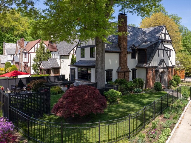 exterior space featuring a high end roof, a front lawn, stucco siding, a chimney, and fence private yard