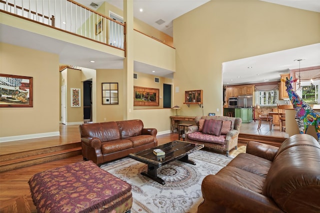 living room with baseboards, wood finished floors, and a towering ceiling