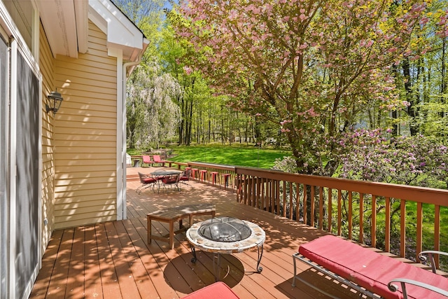 deck with a yard, outdoor dining area, and an outdoor fire pit