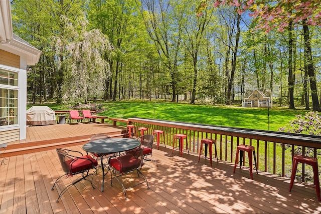 wooden terrace featuring a lawn, outdoor dining area, and area for grilling